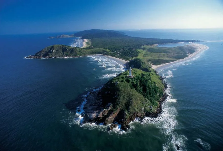 Vista aérea da Ilha do Mel, com o Farol das Conchas, mata nativa e mar azul